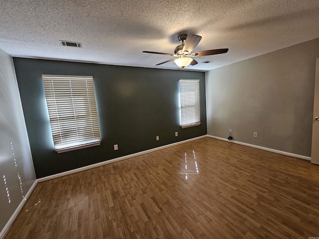 empty room featuring ceiling fan, dark wood-type flooring, and a textured ceiling