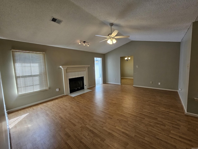 unfurnished living room with ceiling fan, a fireplace, wood-type flooring, and vaulted ceiling