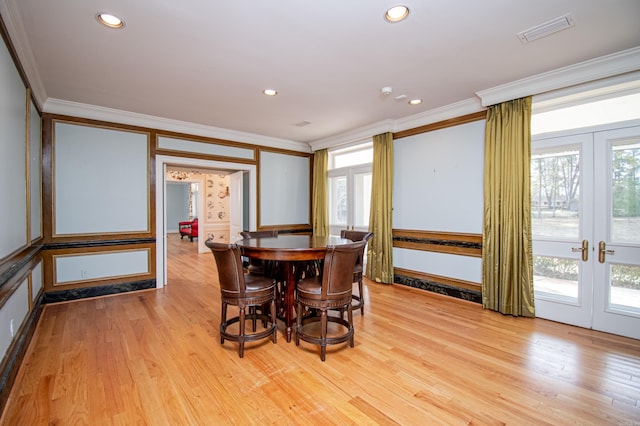 dining space with a wealth of natural light, crown molding, french doors, and light hardwood / wood-style flooring