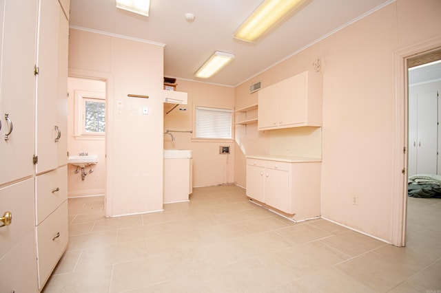 kitchen featuring white cabinetry, sink, and ornamental molding