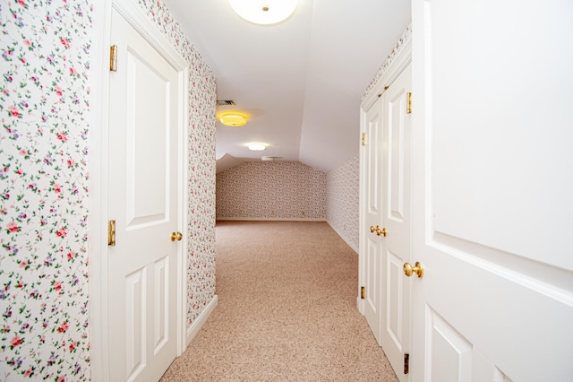 hall featuring light colored carpet and vaulted ceiling