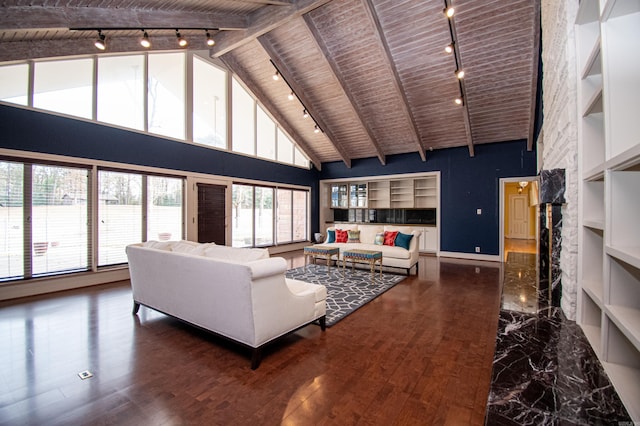 living room with a healthy amount of sunlight, a stone fireplace, built in features, and wood ceiling