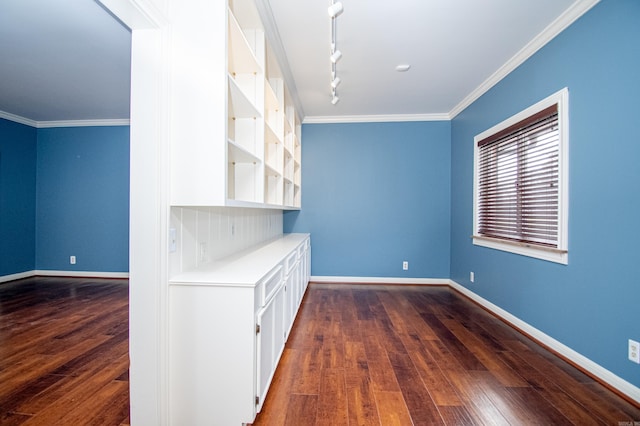 interior space with dark hardwood / wood-style floors, white cabinetry, ornamental molding, and track lighting