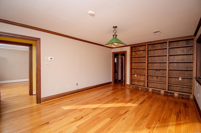 unfurnished room with built in shelves, wood-type flooring, and crown molding