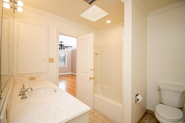 bathroom featuring a skylight, vanity, ceiling fan, crown molding, and toilet