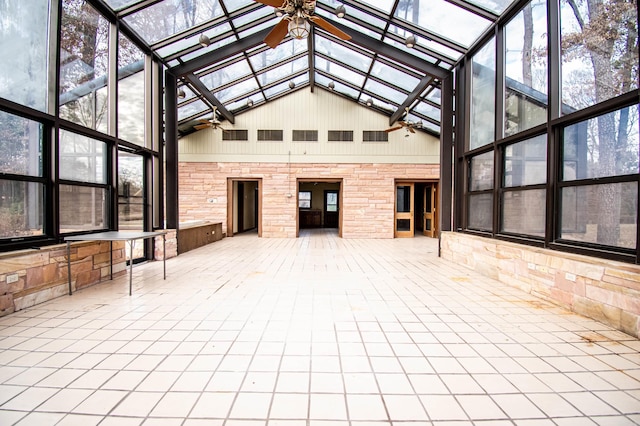 unfurnished sunroom with vaulted ceiling with skylight, ceiling fan, and a wealth of natural light