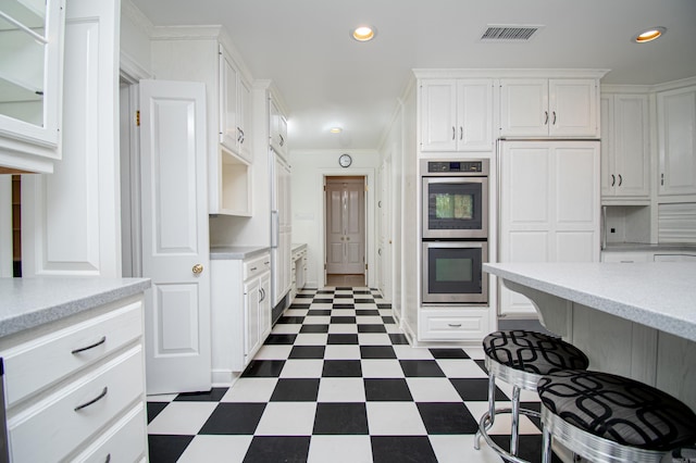 kitchen with white cabinetry, double oven, and crown molding