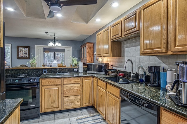 kitchen featuring black appliances, dark stone countertops, sink, and an inviting chandelier