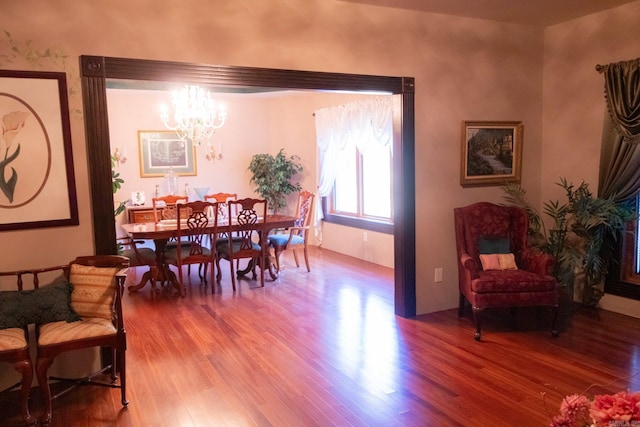 dining space featuring wood-type flooring and an inviting chandelier