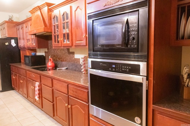 kitchen featuring black appliances, custom exhaust hood, light tile patterned floors, and tasteful backsplash