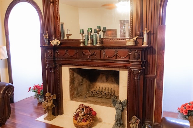 details with hardwood / wood-style flooring, ceiling fan, and a tile fireplace