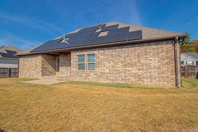 back of property with a yard and solar panels