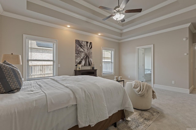 bedroom with crown molding, a tray ceiling, ensuite bath, and carpet