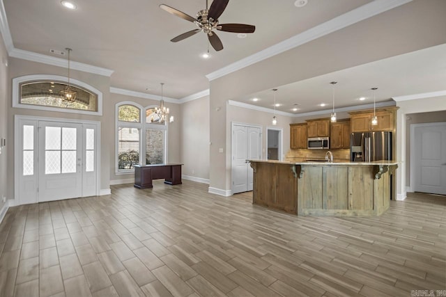 kitchen with a spacious island, crown molding, hanging light fixtures, and appliances with stainless steel finishes