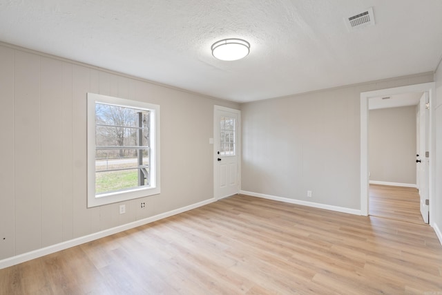 unfurnished room with crown molding, a textured ceiling, and light hardwood / wood-style flooring