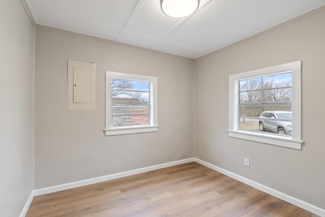 unfurnished room with electric panel and light hardwood / wood-style flooring