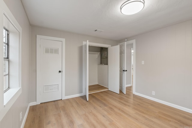 unfurnished bedroom featuring a textured ceiling, light hardwood / wood-style flooring, and a closet