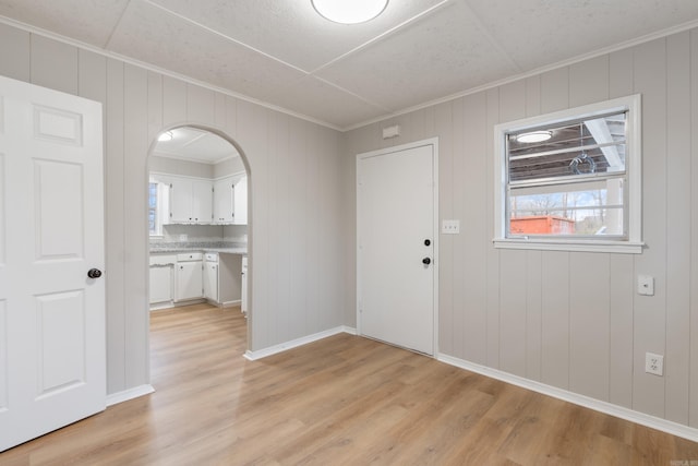 entryway with light hardwood / wood-style flooring and crown molding