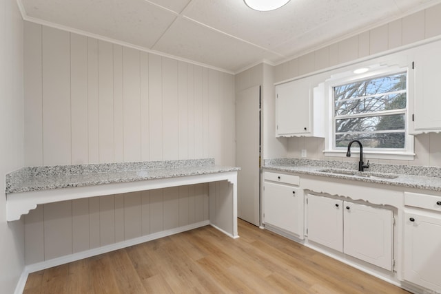 kitchen with white cabinets, crown molding, sink, and light hardwood / wood-style flooring