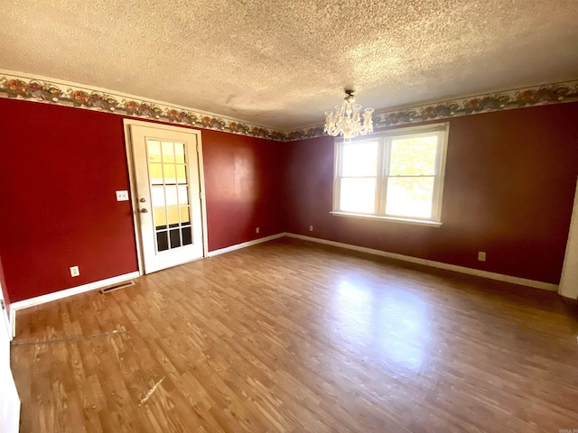 unfurnished room featuring hardwood / wood-style floors, a textured ceiling, and a notable chandelier