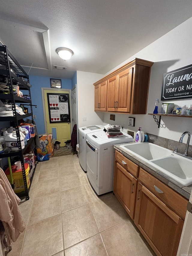 laundry room featuring cabinets, sink, washing machine and dryer, light tile patterned floors, and a textured ceiling