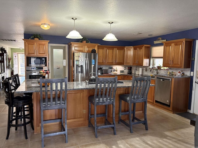 kitchen featuring stone counters, a kitchen island with sink, and appliances with stainless steel finishes