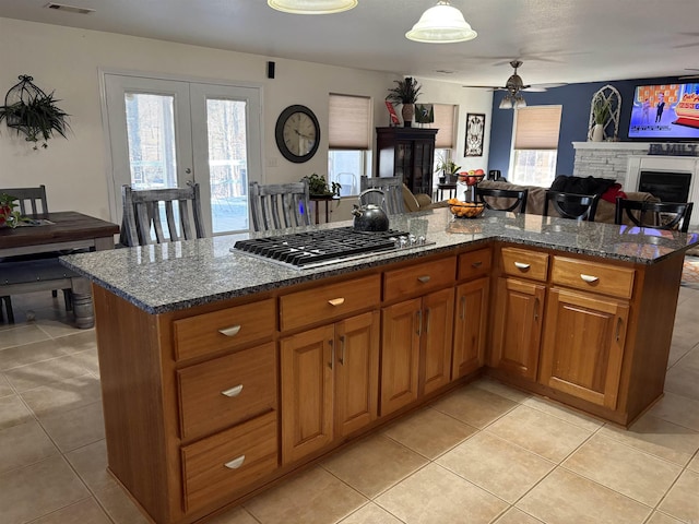 kitchen featuring french doors, dark stone counters, stainless steel gas cooktop, ceiling fan, and light tile patterned floors