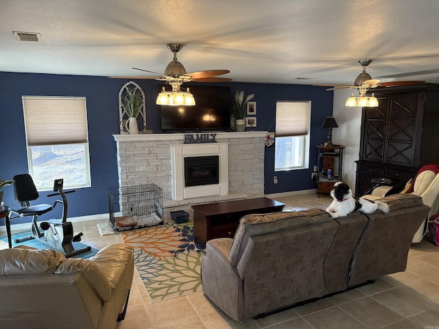 living room featuring light tile patterned floors, a textured ceiling, and ceiling fan