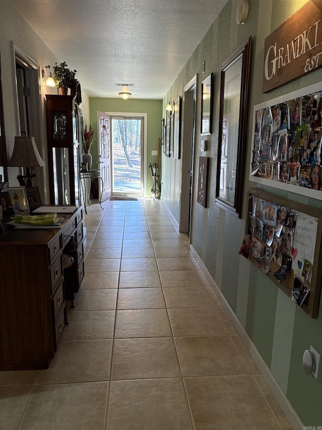 hall featuring light tile patterned floors and a textured ceiling