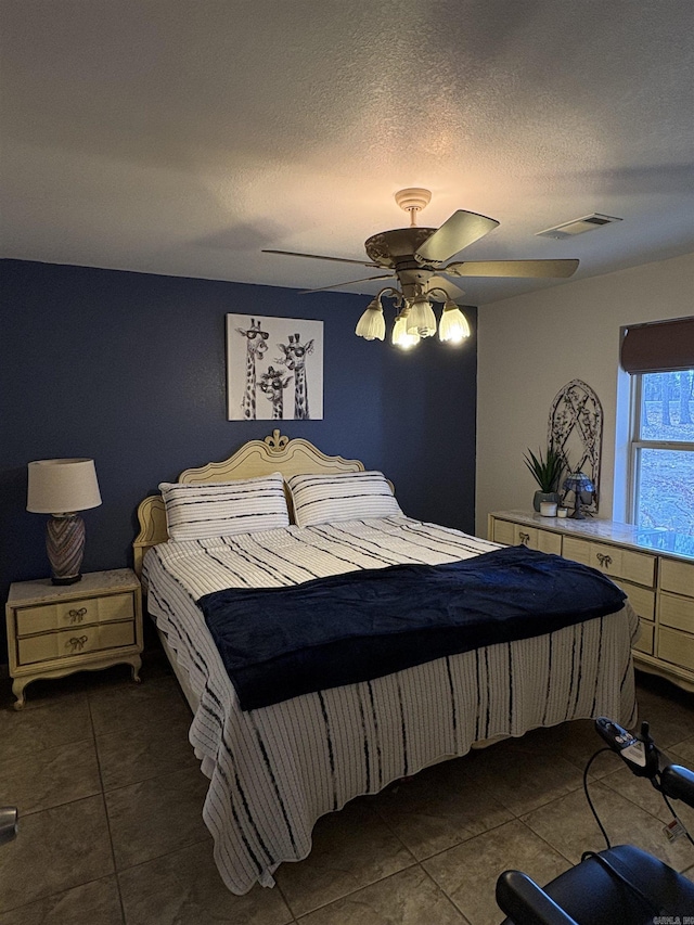 bedroom featuring dark tile patterned flooring, ceiling fan, and a textured ceiling