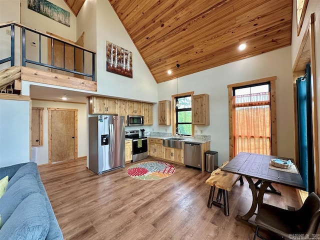 kitchen with appliances with stainless steel finishes, a towering ceiling, hardwood / wood-style flooring, and wood ceiling