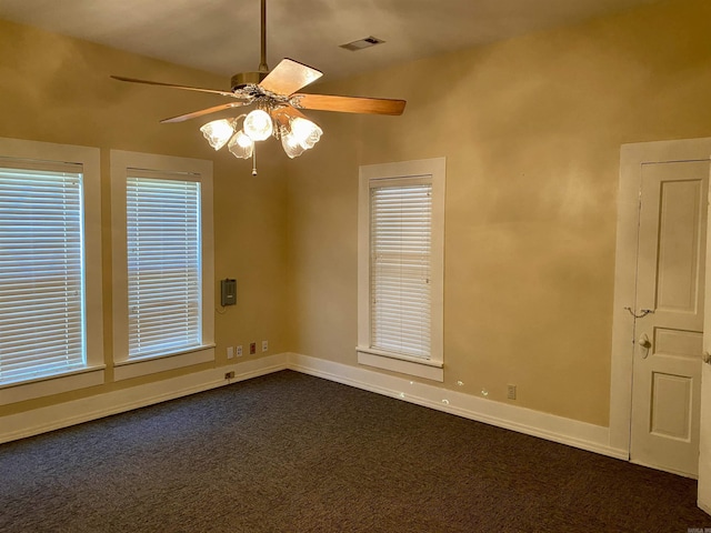 empty room with dark colored carpet and ceiling fan