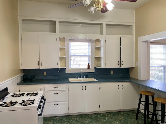 kitchen with white cabinets, white gas range, and sink