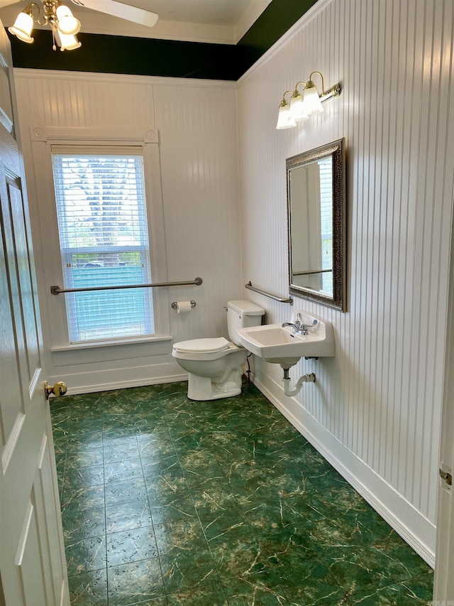 bathroom featuring toilet, wooden walls, and sink