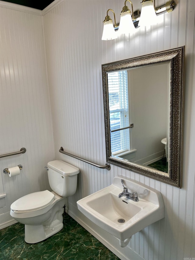 bathroom with wooden walls, sink, and toilet