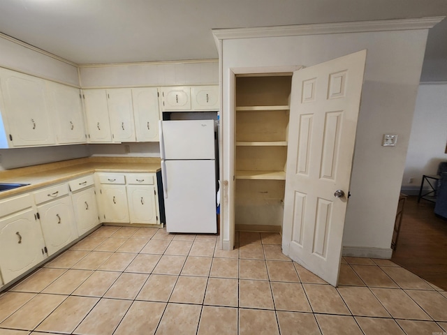 kitchen with white fridge, sink, light tile patterned floors, and ornamental molding