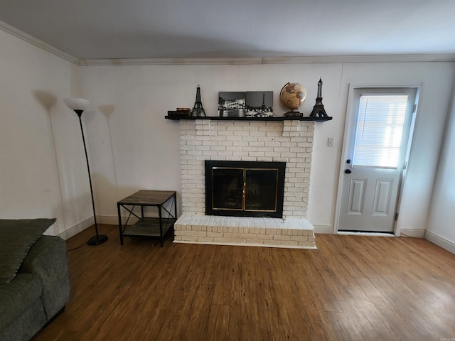 living room featuring wood-type flooring, a brick fireplace, and ornamental molding