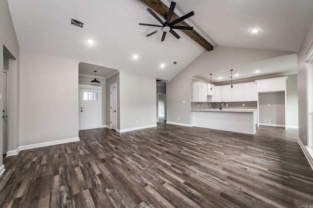 unfurnished living room with ceiling fan, sink, dark wood-type flooring, beamed ceiling, and high vaulted ceiling