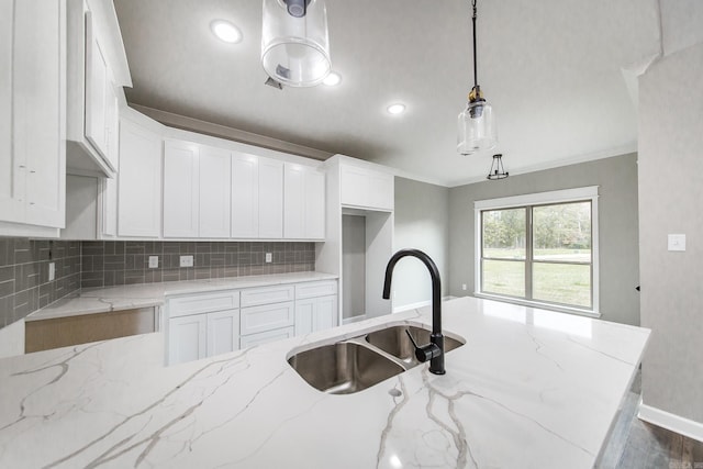 kitchen featuring sink, light stone countertops, tasteful backsplash, decorative light fixtures, and white cabinetry