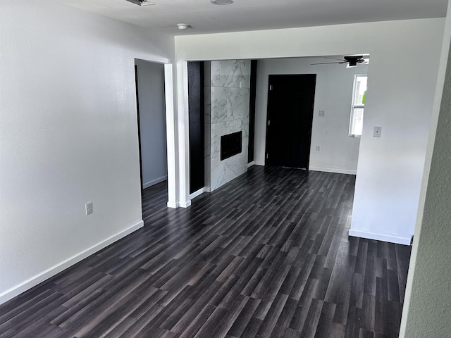 spare room featuring dark hardwood / wood-style floors, ceiling fan, and a fireplace