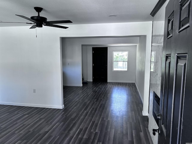 unfurnished living room with ceiling fan, a textured ceiling, and dark hardwood / wood-style flooring