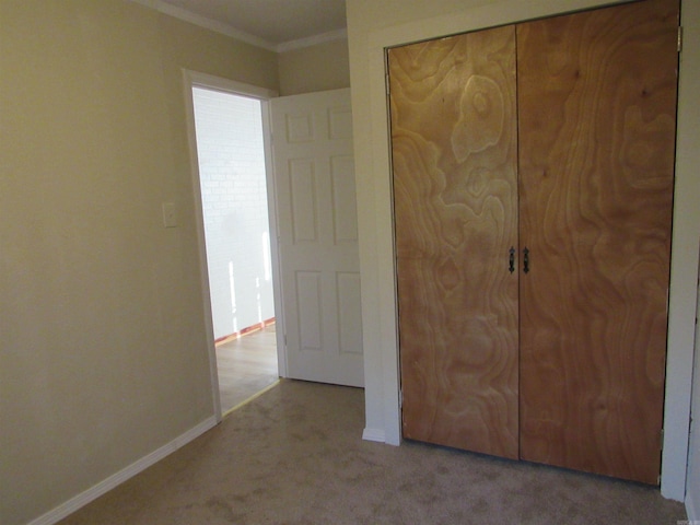 unfurnished bedroom with a closet, light colored carpet, and ornamental molding