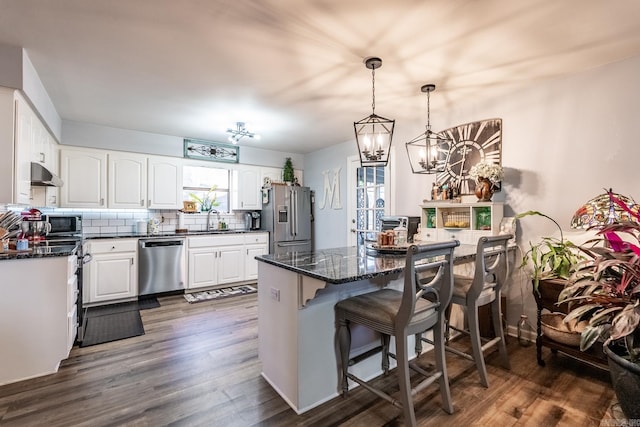 kitchen featuring decorative backsplash, appliances with stainless steel finishes, sink, white cabinets, and hanging light fixtures