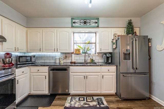 kitchen featuring tasteful backsplash, stainless steel appliances, dark wood-type flooring, sink, and white cabinets