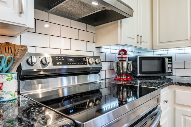 kitchen with decorative backsplash, stainless steel appliances, extractor fan, dark stone countertops, and white cabinetry