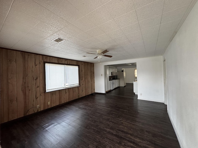 interior space featuring ceiling fan, wood walls, and dark hardwood / wood-style floors