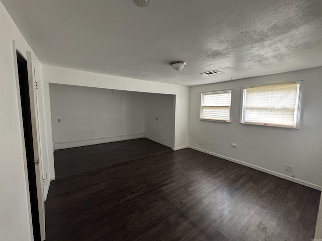 unfurnished room featuring dark hardwood / wood-style flooring and a textured ceiling