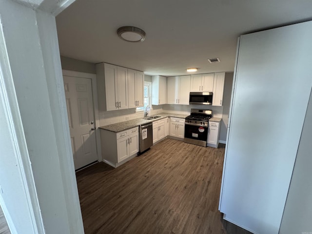 kitchen featuring light stone countertops, dark hardwood / wood-style flooring, stainless steel appliances, sink, and white cabinetry