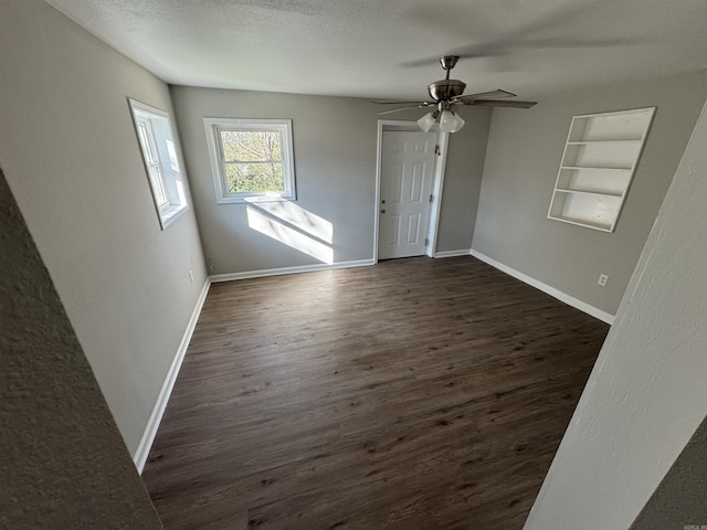 spare room featuring a textured ceiling, dark hardwood / wood-style flooring, built in features, and ceiling fan