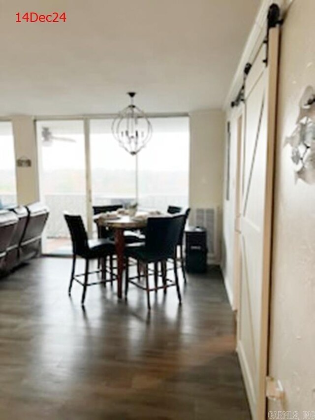 dining area featuring a barn door, dark wood-type flooring, and an inviting chandelier